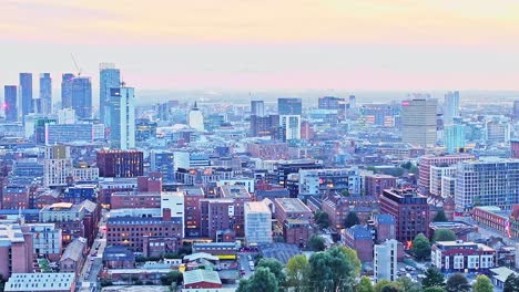 zoomed drone lifting shot of the illuminated skyline of manchester after sunset