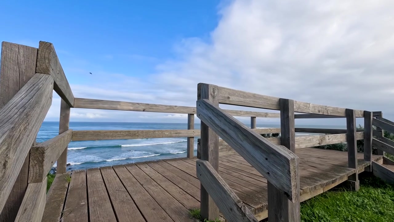 Camera moves toward a wooden lookout platform revealing scenic ocean views in Flinders, Australia.