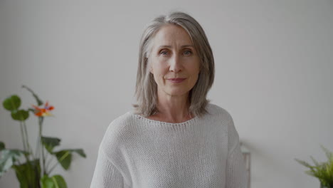 senior woman with gray hair and white shirt looking at camera smiling