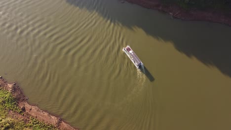 a dynamic aerial shot of a tourist transport boat in motion while turning around to return from its origin