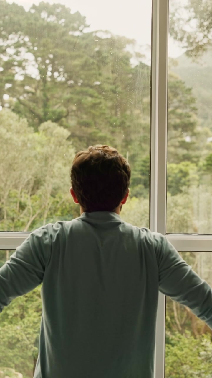 Man Opening Curtains to Reveal Forest View