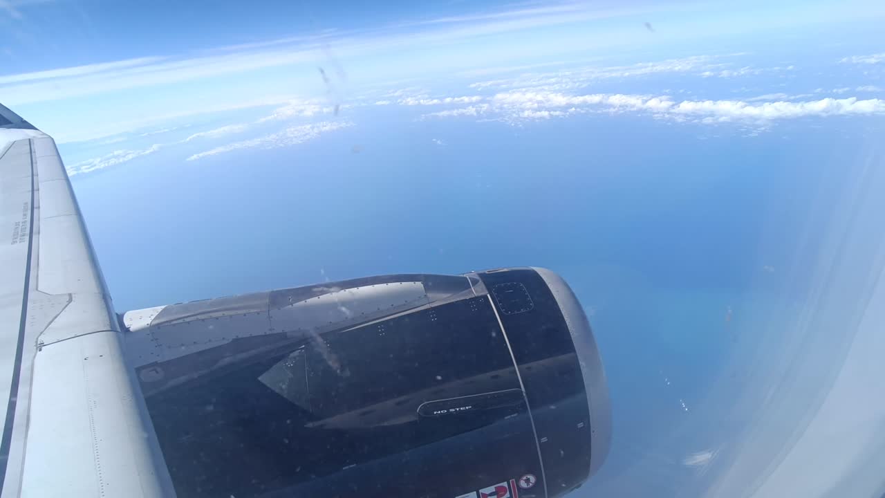 disparo estático mirando hacia fuera sobre el ala de un avión con nubes y el océano debajo