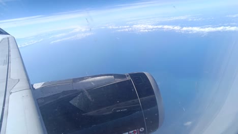 Static-shot-looking-out-over-the-wing-of-an-aeroplane-with-clouds-and-the-ocean-below