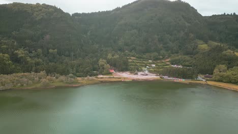 Scenic-aerial-view-of-Furnas-Lake-surrounded-by-lush-green-forests-in-Azores,-Portugal