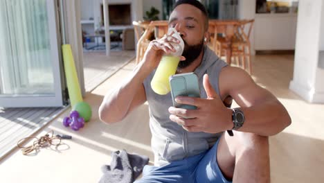 happy african american man resting making video call using smartphone at sunny home, slow motion