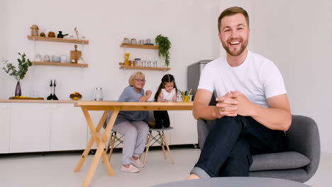 happy handsome man sitting on chair looking at camera while having a video call at home