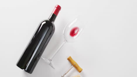 Una-Botella-De-Vino-Tinto-Se-Encuentra-Junto-A-Un-Vaso-Inclinado,-Con-Espacio-Para-Copiar