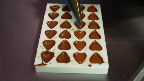 worker filling chocolate moulds with melted chocolate