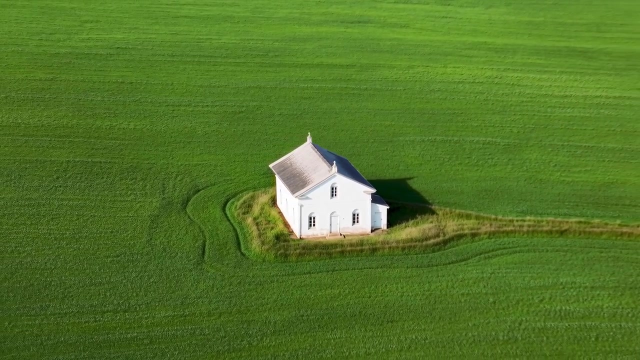 Et hvitt hus står på en grønn eng, med hvitt hus, grønt gress, fra et luftperspektiv, med grønne, hvite aksenter, og en rolig og fredelig stemning, nærliggende objekter, omkringliggende sted.