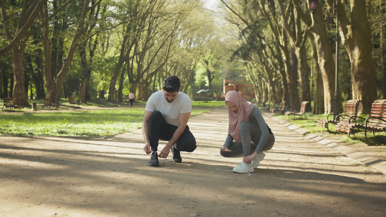 un par atando zapatos en el parque.