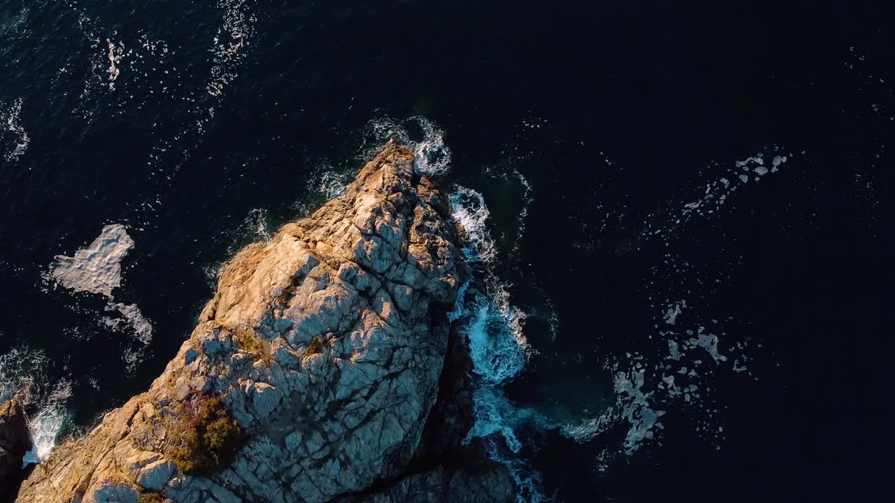imágenes cautivadoras de un avión no tripulado de una isla rocosa en el mar mediterráneo, filmado desde arriba mientras gira, mostrando vibrantes aguas azules y turquesas