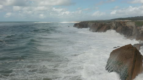 volando sobre un mar salvaje con olas rompiendo en acantilados rocosos