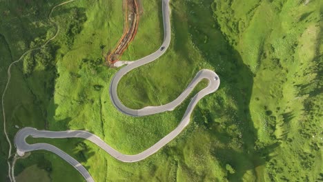 Aerial-tilt-up-view-of-cars-driving-on-the-winding-road-of-Passo-Gardena-in-the-Dolomites-Mountains,-Trentino,-South-Tyrol,-Italy