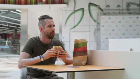 man eating a burger in a mall