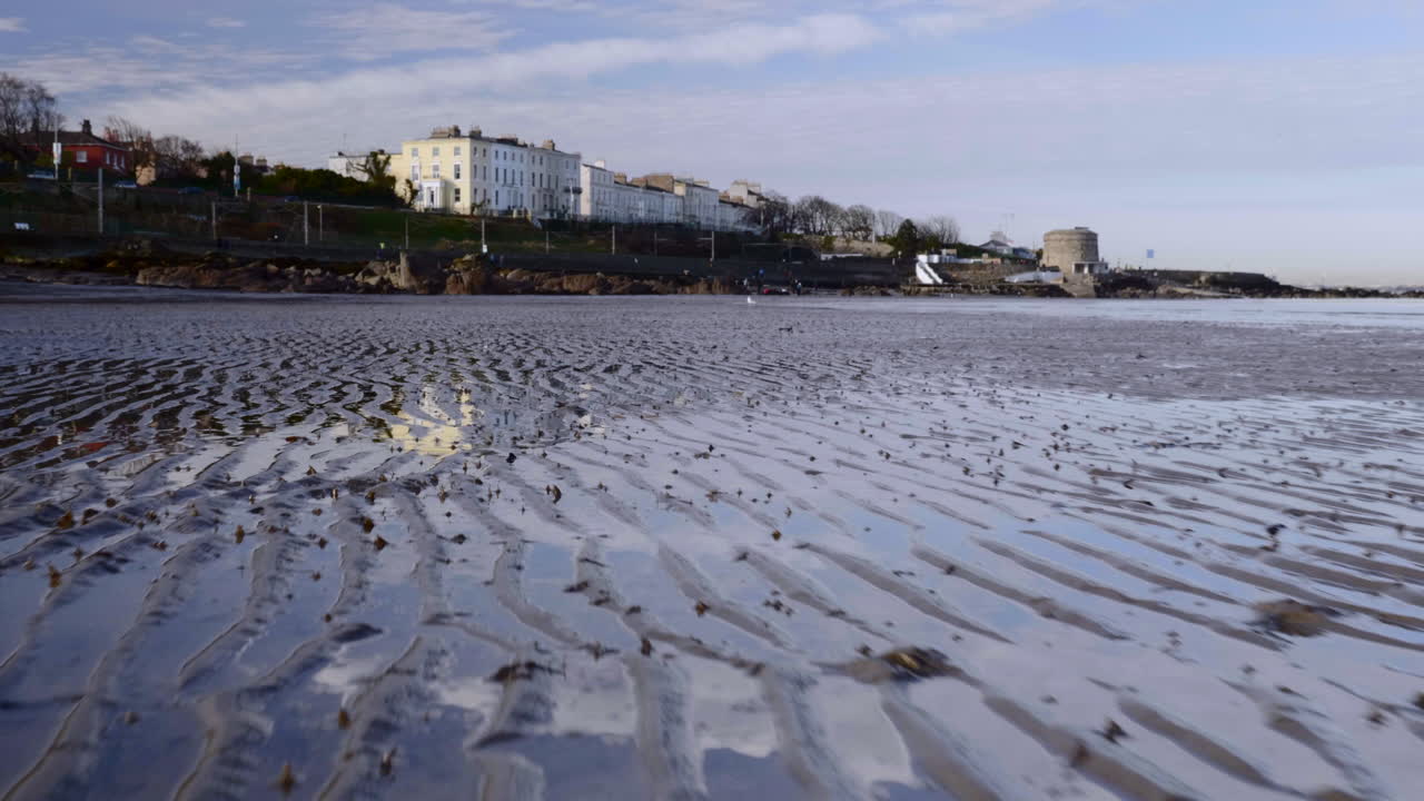 дрон пролетает над болотистой землей в южной ирландии с современными зданиями на заднем плане - низкий аэрофотоснимок