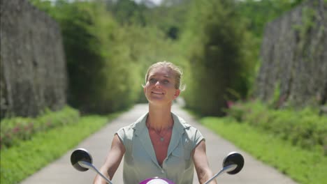 Frau,-Die-Scooter-An-Einem-Sonnigen-Tag-Auf-Einem-Tropischen-Pfad-Im-Resort-Fährt,-Reise-In-Bali