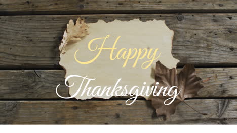 animation of happy thanksgiving text over autumn leaves and paper on wooden boards