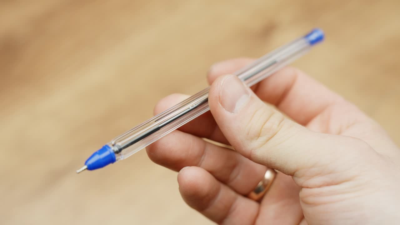 Person holds blue pen, close up POV view