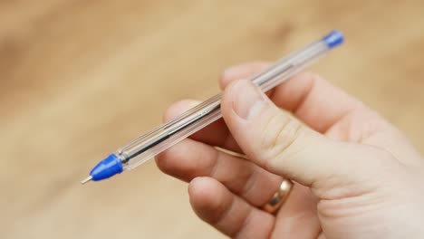 person holds blue pen, close up pov view