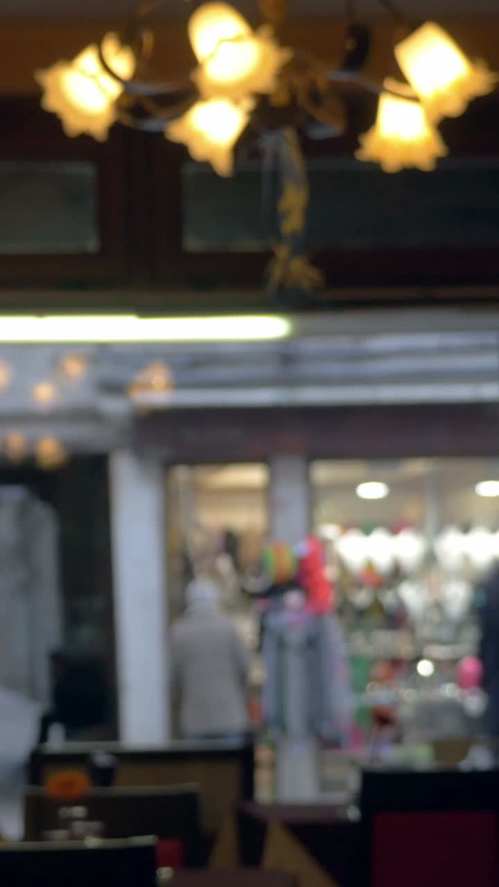Vista sfocata di una vetrina con lampadario e persone