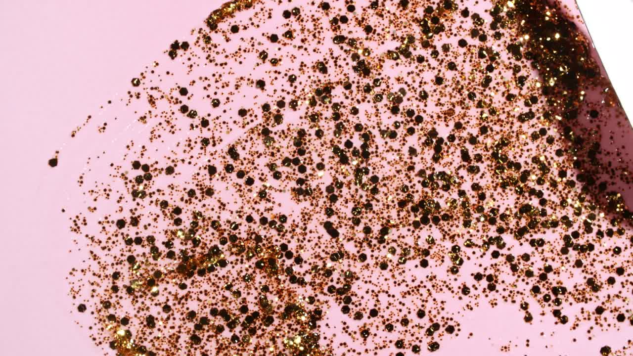 las pinceladas de pintura dorada aplicadas aisladas en un fondo rosado. la textura de la pintura dorada. el brillo, las estrellas, las chispas. la ilustración artística de textura dorada brillante. las manchas de cosméticos.