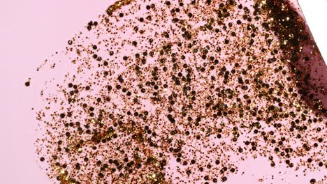 brushstrokes of gold paint brush applied isolated on a pink background. gold paint smear texture. shine, stars, sparkles. golden sparkling textured artistic illustration. smears of cosmetics.