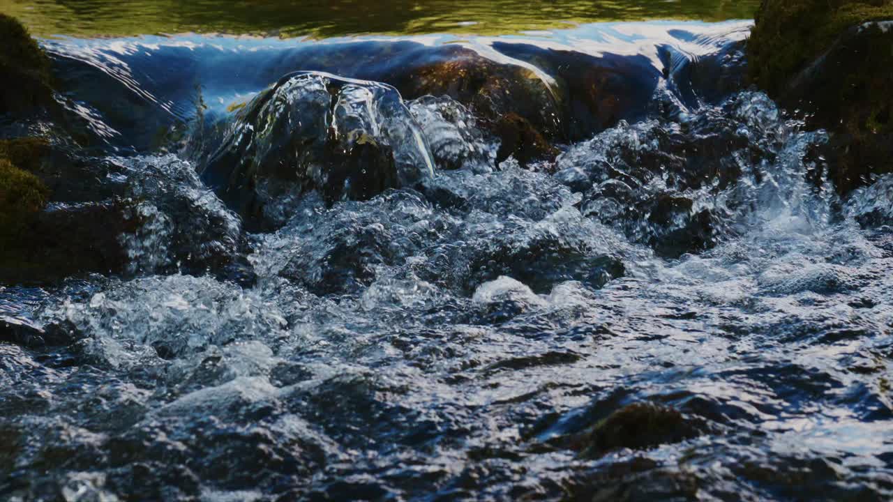 Fiume impetuoso scorre su rocce muschiose. L'acqua si infrange e schizza con forza. Ombre e luci definiscono la scena. Perfetto per temi di natura, avventura o ambientali.
