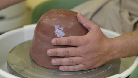 potter starting to make ceramic pot with wet clay on pottery wheel turntable