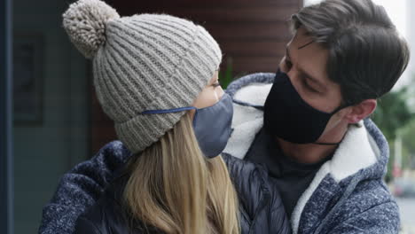 pareja besándose al aire libre mientras llevan máscaras