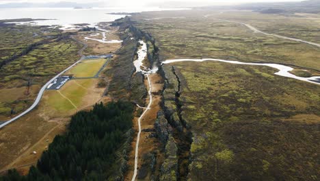 aerial of beautiful canyon in thingvellir national park with distant waterfall and lake on a sunny day