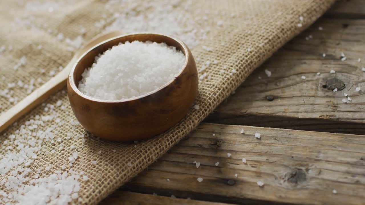 Video of salt in a bowl and spoon on wooden background