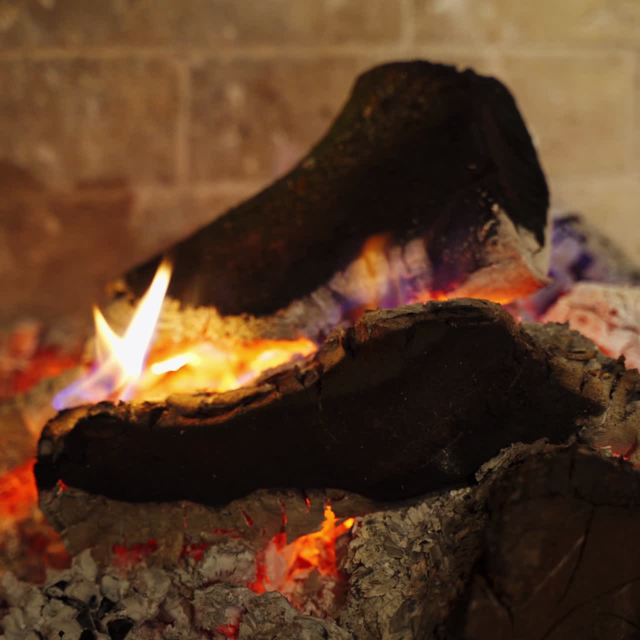 Smoldered logs in white ashes. Background of glowing wood. Black logs burning out in fireplace. Comfortable heat place at home.