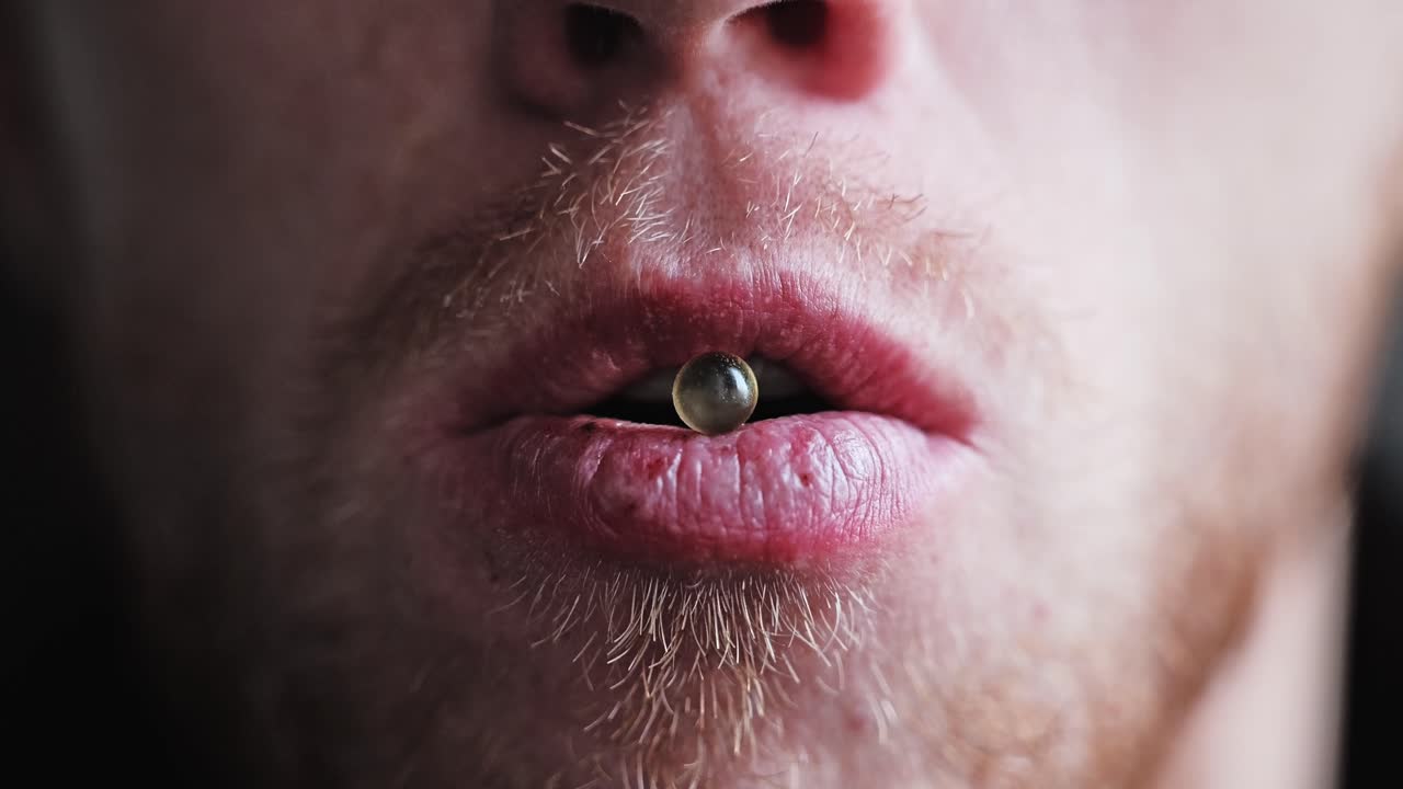 Un primissimo piano mostra una capsula tra le labbra, a simboleggiare il potere sul corpo
