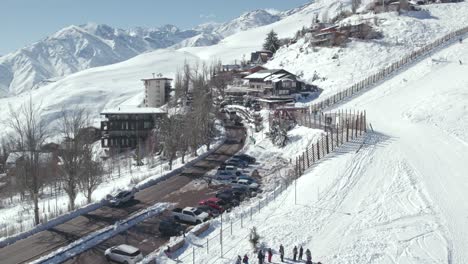 Aerial-Drone-Fly-Above-Farellones-Ski-Resort,-Snowed-Mountain-Town-in-Chile-with-Tourists-and-Andean-Cordillera-Background