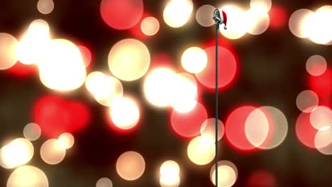 Santa-hat-over-microphone-against-red-and-yellow-spots-of-light-against-black-background