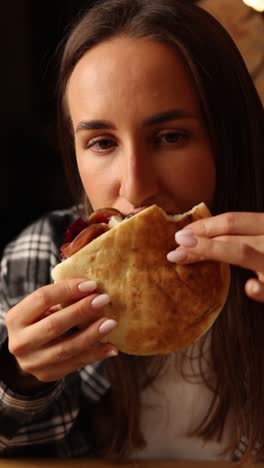 una mujer comiendo un sándwich de pita