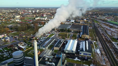 aerial view of a smoking factory chimney, urban city background, sunny fall day