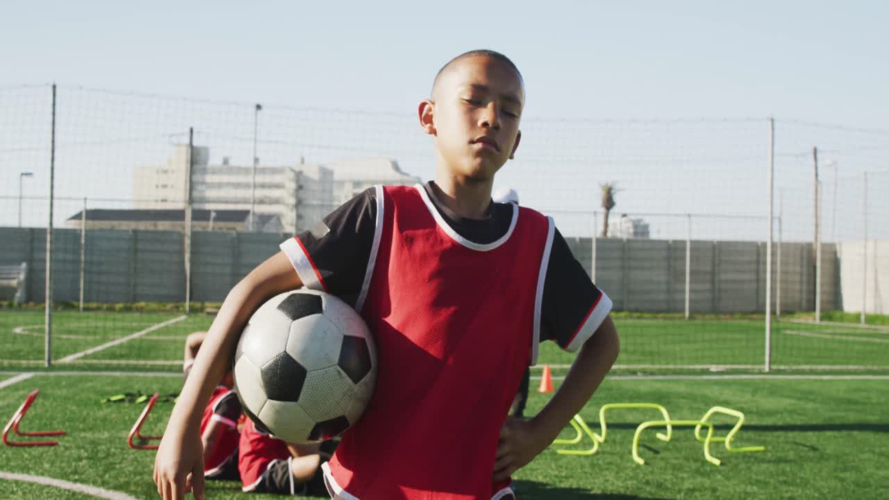 Criança afro-americana jogando futebol se exercitando em um dia ensolarado.