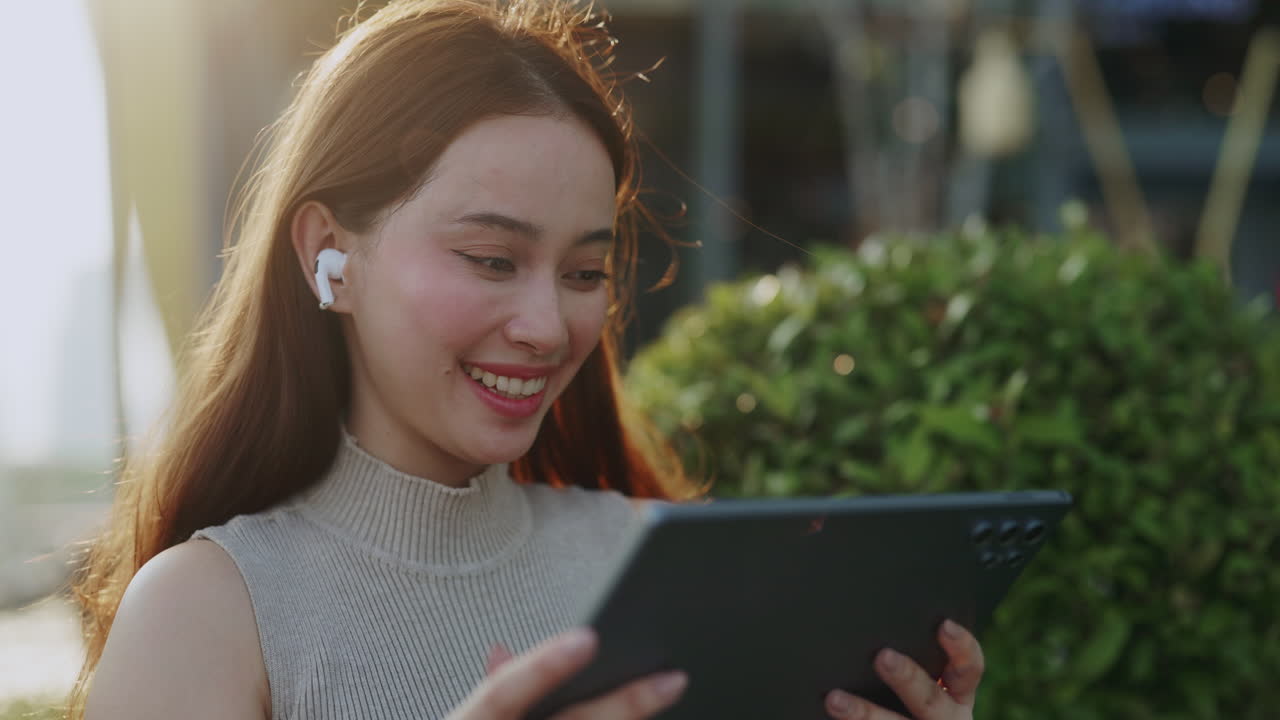 Smiling Young Woman Watching Content on Tablet with Earbuds