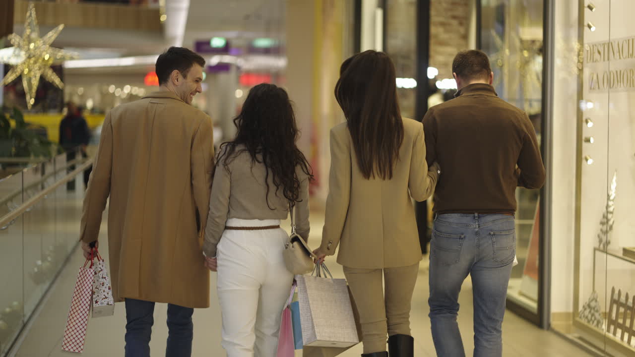 Two couples walking and shopping in a mall
