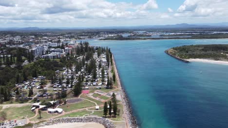 Drone-flying-towards-a-coastal-van-park-showing-a-blue-river-below