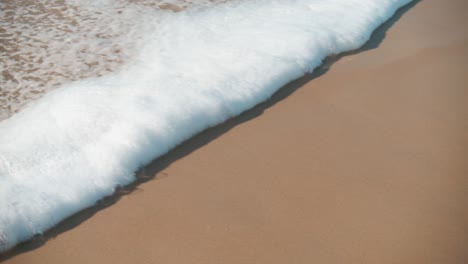 ola de espuma esponjosa que fluye sobre la playa en cámara lenta