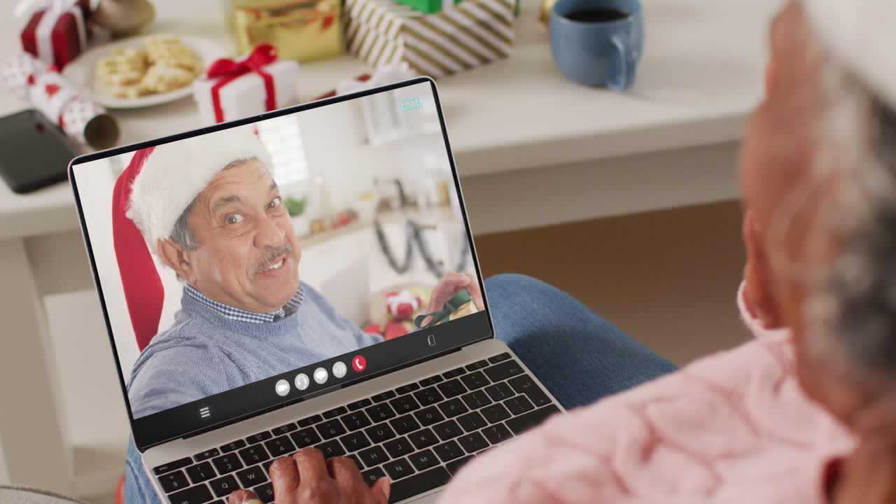 una anciana afroamericana tiene una videollamada de navidad con un anciano biracial.