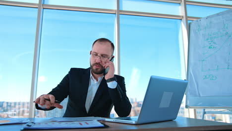confident business person talking the phone in office. portrait of a boss sitting at table and dealing business problems through the phone.