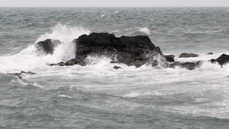 waves crashing on rocks on the west coast of scotland in the village of port patrick