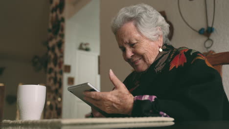 aged woman with gadget sitting at table