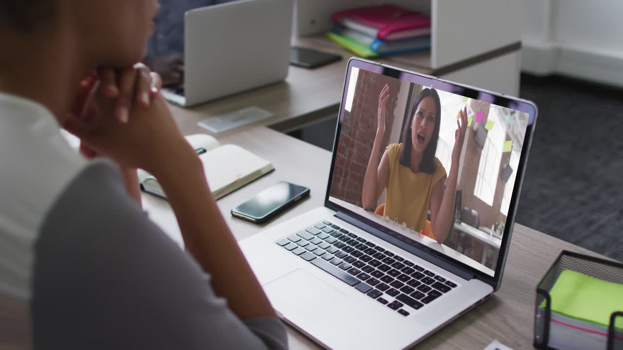 Mid section of african american woman having a video call on laptop with female colleague at office