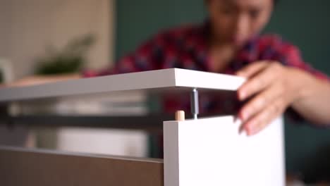 mujer anónima montando muebles en la habitación