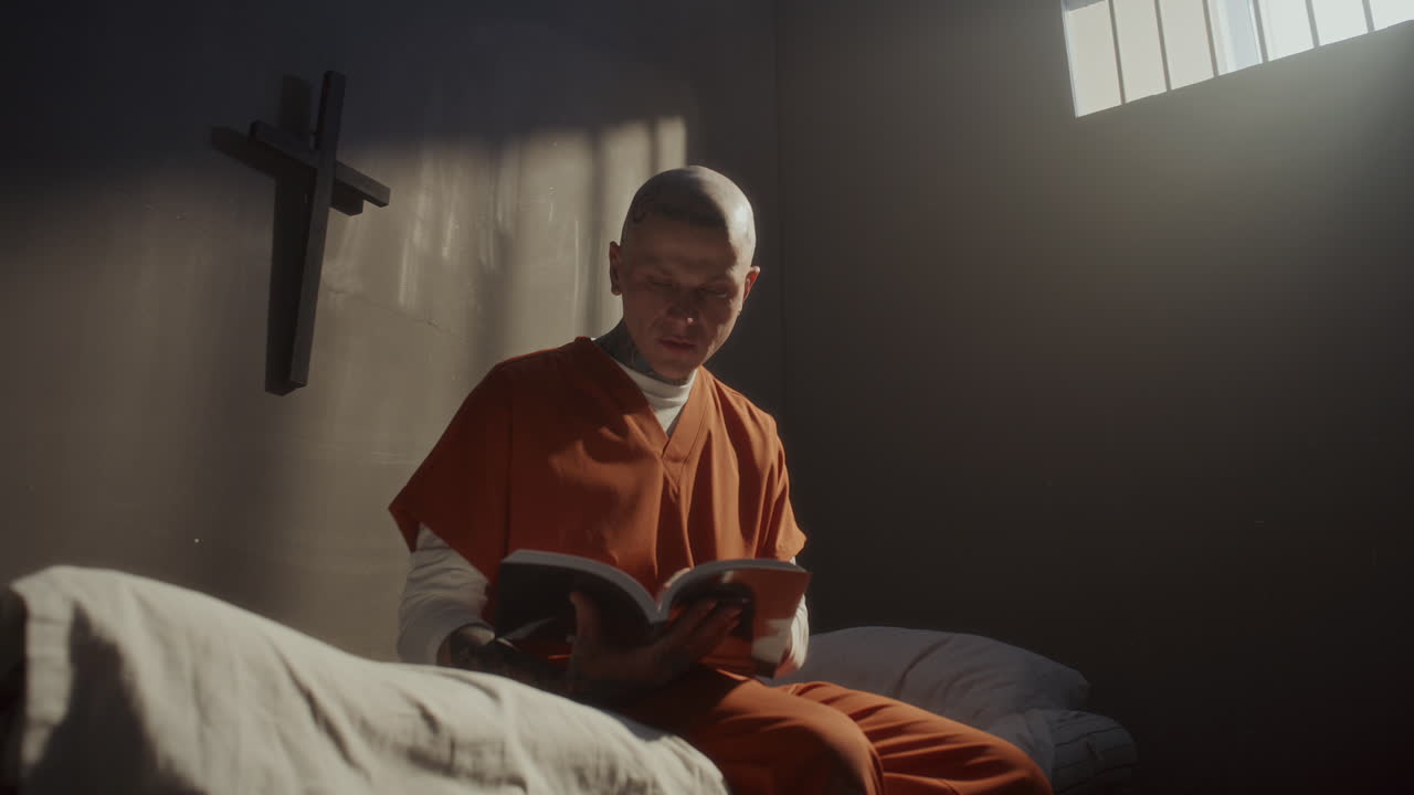 Tattooed Inmate Reading Bible on His Bed in Prison Cell