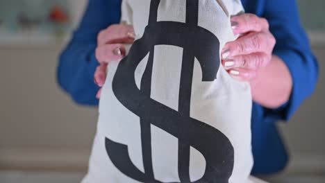 older female picks up money bag and shows it close to the camera